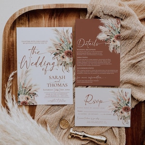 K&ouml;nnte beinhalten: Ein Satz von drei Hochzeitseinladungskarten im rustikalen Stil. Die Karten zeigen ein florales Design mit getrocknetem Pampasgras und einem braunen und wei&szlig;en Farbschema. Der Text auf den Karten lautet "Die Hochzeit von Sarah und Thomas" und enth&auml;lt das Datum und die Uhrzeit der Hochzeit. Die RSVP-Karte enth&auml;lt einen Platz f&uuml;r die G&auml;ste, um ihre Teilnahme zu best&auml;tigen.