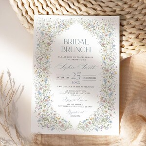 May include: A floral-themed bridal brunch invitation with a watercolor border of blue, pink, and yellow flowers. The text reads "Bridal Brunch", "Please join us to celebrate the bride-to-be", "Sophie Smith", "Saturday 25 December 20XX", "Two o'clock in the afternoon", "At this location", "121 Anywhere St., Any City, ST 12345", "RSVP to Lauren", "on or before November 15th at (123) 45 7890", "Register at AMAZON".