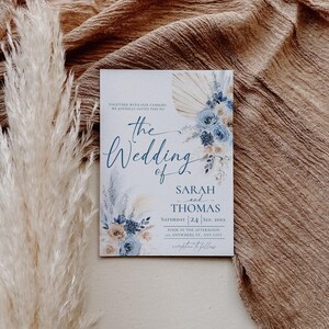 May include: A wedding invitation with a blue and beige floral design. The text reads "Together with our families we joyfully invite you to the wedding of Sarah and Thomas, Saturday 24 Sep, 20XX, Four in the afternoon, at Anywhere St, Any City, reception to follow."