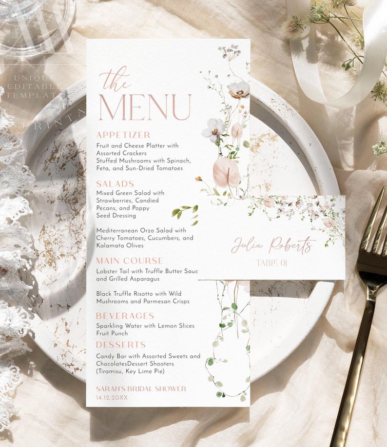 May include: A white menu card with floral illustrations and pink text listing appetizers, salads, main courses, beverages, and desserts for Sarah's Bridal Shower. A smaller matching place card with the name Julia Roberts is placed on top.