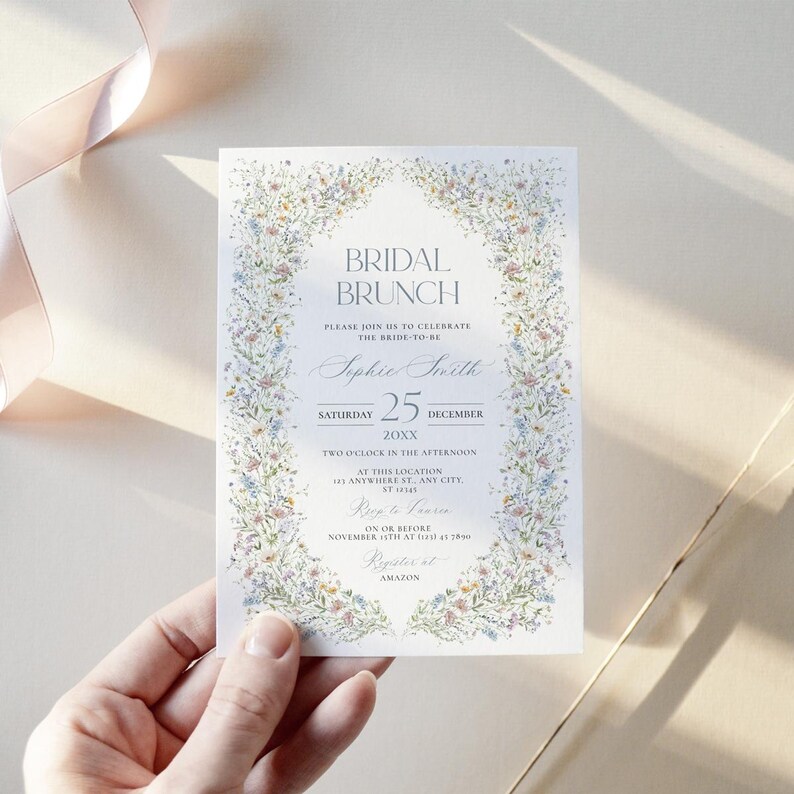 May include: A floral-themed bridal brunch invitation with a watercolor design. The invitation features a wreath of flowers and greenery surrounding the text "Bridal Brunch". The text "Sophie Smith" is written in cursive script, and the date is "Saturday, 25 December 20XX". The invitation also includes the time, location, and RSVP information.