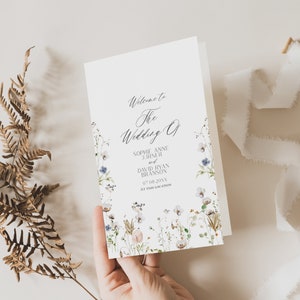 May include: A white wedding program with a floral border. The text reads "Welcome to the Wedding of Sophie Anne Jurner and David Ryan Branson 07.08.20XX at this location."
