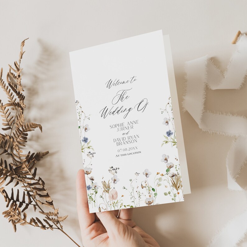 May include: A white wedding program with a floral border. The text reads "Welcome to the Wedding of Sophie Anne Jurner and David Ryan Branson 07.08.20XX at this location."