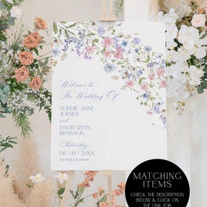K&ouml;nnte beinhalten: Ein wei&szlig;es, rechteckiges Hochzeitsschild mit einem Aquarell-Blumenarrangement aus rosa, blauen und violetten Wildblumen. Der Text lautet: Welcome to The Wedding Of SOPHIE ANNE JURNER and DAVID RYAN BRANSON Saturday 08 | 10 | 20XX AT THIS LOCATION.