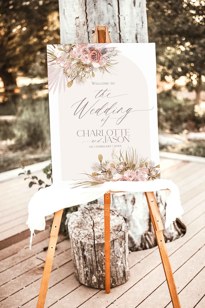 May include: A wedding welcome sign with a floral design in shades of pink, beige, and green. The sign reads "Welcome to the Wedding of Charlotte and Jason 02 | February | 20XX".