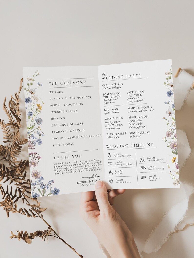 May include: A white wedding program card featuring floral illustrations in blue, purple, and yellow along the sides. The text includes sections for The Ceremony, The Wedding Party, and a Wedding Timeline, ending with a Thank You note from Sophie and David.