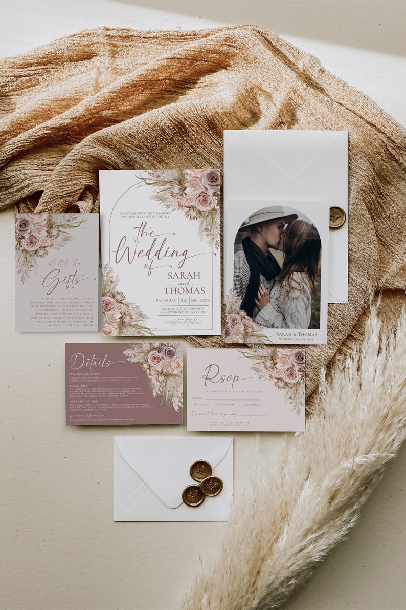 May include: A wedding invitation suite featuring a main card, RSVP card, details card, and gift note. The stationery displays floral illustrations in muted pink and brown tones, elegant script typography, and a photo of a couple.