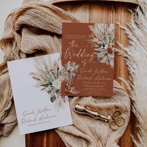 May include: A wedding invitation set featuring a rust-coloured card and a white card, both decorated with pampas grass and floral illustrations. The rust card displays a cowboy boot graphic and text including the names Sarah William and Richard Anderson. A gold wax seal stamp and two wax seals are included.