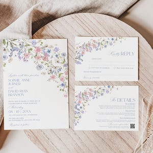 K&ouml;nnte beinhalten: Ein Hochzeitseinladungsset bestehend aus einer Hauptkarte, einer Antwortkarte und einer Detailkarte. Jede wei&szlig;e Karte zeigt einen zarten Aquarell-Blumenrand in Rosa, Blau und Gr&uuml;n mit aufgedrucktem Text zu den Veranstaltungsdetails.