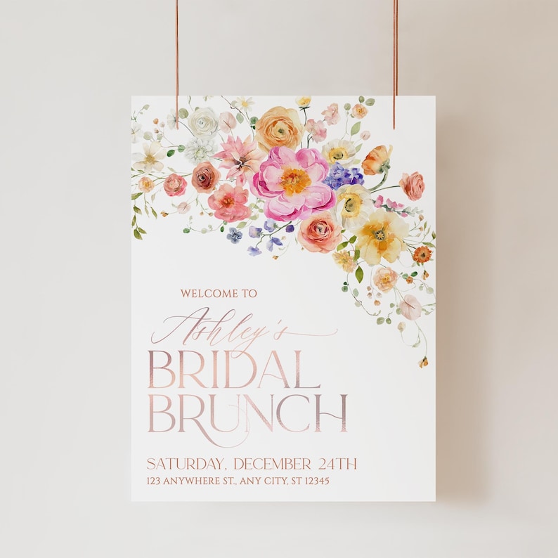 May include: A white rectangular sign featuring a watercolor floral arrangement in pink, orange, and yellow at the top. The text reads: WELCOME TO Ashley's BRIDAL BRUNCH SATURDAY, DECEMBER 24TH 123 ANYWHERE ST., ANY CITY, ST 12345 in rose gold.