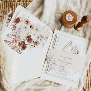 May include: A wedding invitation suite with a geometric design and floral accents. The invitation features a gold triangle with a floral illustration and the text "Sarah Hooper and Thomas Anderson, 09.24.2023, Saturday | Five O'Clock, at [Location], reception to follow".
