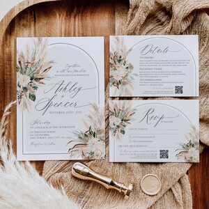 Puede incluir: Un conjunto de invitaciones de boda con una tarjeta principal, una de detalles y una de RSVP con marcos arqueados e ilustraciones de hierba de la pampa. El texto incluye los nombres Ashley y Spencer, detalles del evento, c&oacute;digos QR y un sello.