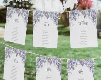 Puede incluir: Seis tarjetas de mesa rectangulares blancas colgadas de un cordel. Cada tarjeta presenta una ilustración floral morada en la parte superior y enumera los números de mesa del uno al seis con nombres impresos en negro.
