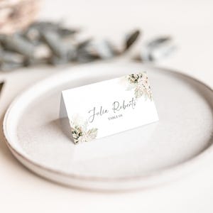 May include: A white place card with a watercolor floral design and the text "Julie Roberts, Table 04".