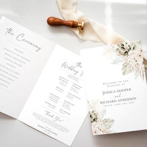 May include: A folded wedding program and a separate invitation card featuring floral illustrations in muted tones. The text includes the names Jessica Hooper and Richard Anderson, the date September 25th, 2023, and a ceremony outline. A wooden wax seal stamp rests nearby.
