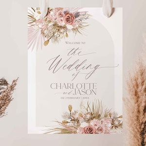 May include: A wedding welcome sign with a floral design in shades of pink and beige. The sign reads "Welcome to the Wedding of Charlotte and Jason 02 | February | 20XX".