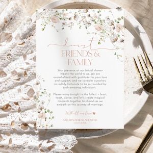 May include: A rectangular white card featuring a floral border of pink and green watercolor flowers. The text reads: dearest FRIENDS & FAMILY. Your presence at our bridal shower means the world to us. SARAH'S BRIDAL SHOWER 02.07.20XX.