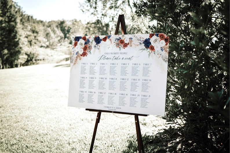 May include: A white wedding seating chart with a floral design in shades of red, blue, and white. The chart lists tables 1 through 21 and includes the text "Our Favorite People Please Take a Seat".