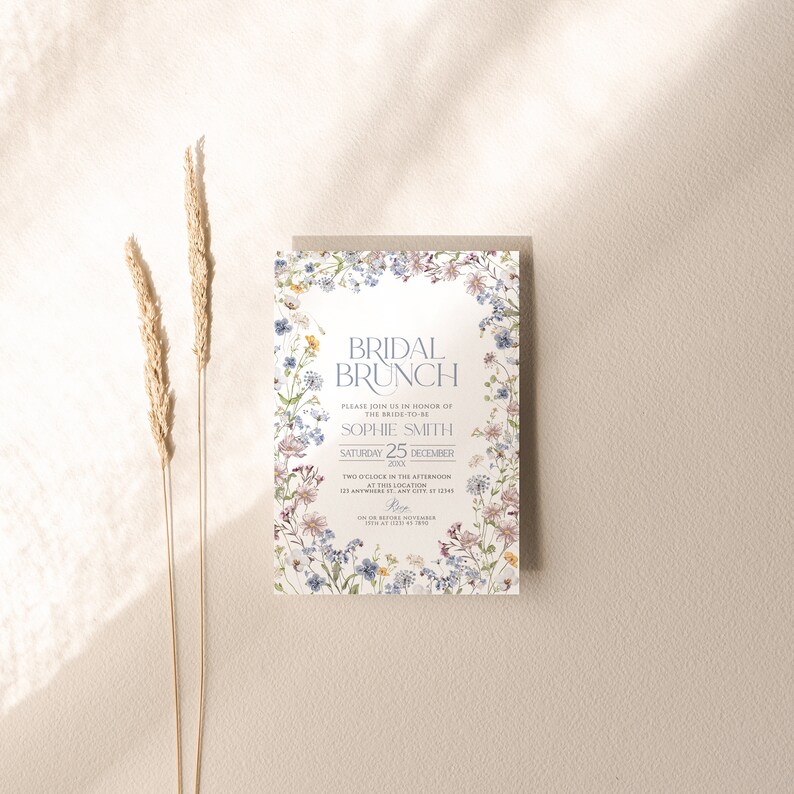 May include: A floral-themed bridal brunch invitation with a white background and a border of watercolor flowers in shades of blue, pink, and yellow. The text reads "Bridal Brunch" in a blue font, followed by "Please join us in honor of the bride-to-be Sophie Smith Saturday 25 December 20XX Two o'clock in the afternoon at [Location] 123 Anywhere St, Any City, IT 12345 RSVP by [Date] at [Time] on [Website]"