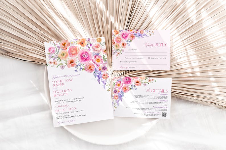 May include: A wedding invitation suite featuring a main invitation, a response card, and a details card. Each white card is decorated with watercolor floral illustrations in shades of pink, orange, and purple, with printed text in pink and black ink.