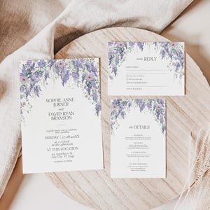 May include: A wedding invitation suite featuring three white cards with purple wisteria floral illustrations at the top. The text includes names Sophie Anne Jurner and David Ryan Branson, event details, a reply card, and a details card.