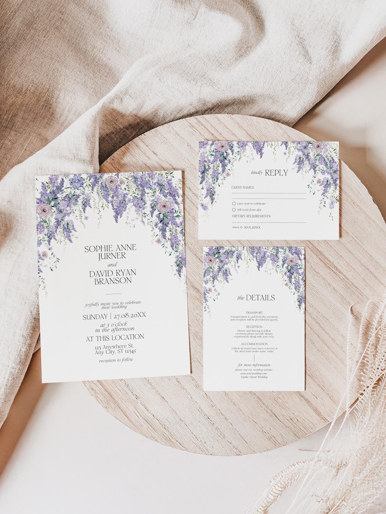 May include: A wedding invitation suite featuring three white cards with purple wisteria floral illustrations at the top. The text includes names Sophie Anne Jurner and David Ryan Branson, event details, a reply card, and a details card.
