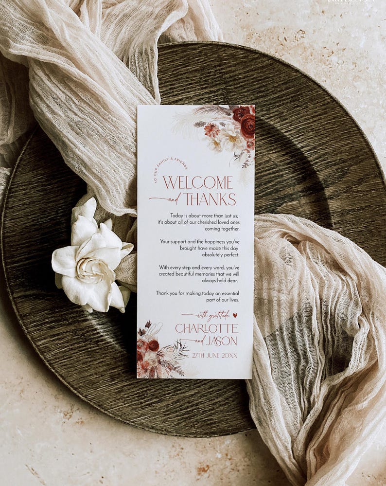 Puede incluir: Una tarjeta de bienvenida rectangular blanca para bodas con ilustraciones florales en tonos burdeos y crema. El texto dice: Welcome and Thanks, Today is about more than just us, Charlotte and Jason, 27th June 20XX, with gratitude.