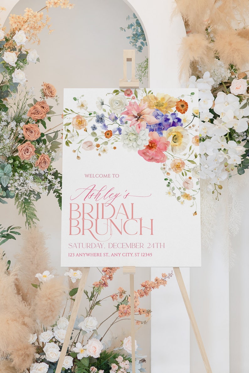 Pu&ograve; includere: Un cartello bianco con un disegno floreale in alto. Il cartello dice "Benvenuti al Brunch Nuziale di Ashley" e include la data e l'indirizzo.