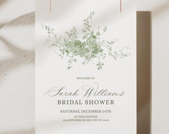 Könnte beinhalten: Eine weiße Einladungskarte mit einem grünen Blumendesign. Der Text lautet "WELCOME TO Sarah Williams BRIDAL SHOWER SATURDAY, DECEMBER 24TH AT THIS LOCATION 123 ANYWHERE ST, ANY CITY, ST 12345". Die Karte hängt an einem dünnen Kupferdraht.