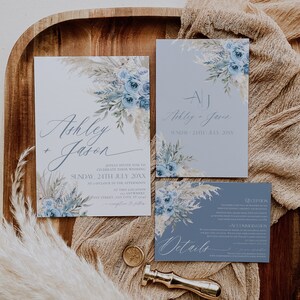 K&ouml;nnte beinhalten: Eine Hochzeitseinladungssuite mit einem blauen und wei&szlig;en Blumendesign. Die Einladung enth&auml;lt die Namen "Ashley + Jason" und das Datum "Sonntag, 24. Juli 20XX". Die RSVP-Karte enth&auml;lt Details zur Rezeption und Unterkunft.