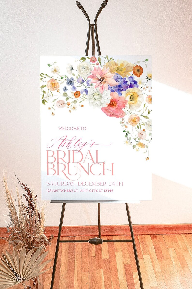 Pu&ograve; includere: Un cartello bianco con un disegno floreale in tonalit&agrave; rosa, giallo, blu e verde. Il testo sul cartello recita "Benvenuti a Ashley's Bridal Brunch, Sabato 24 dicembre, 123 Anywhere St., Any City, ST 12345".