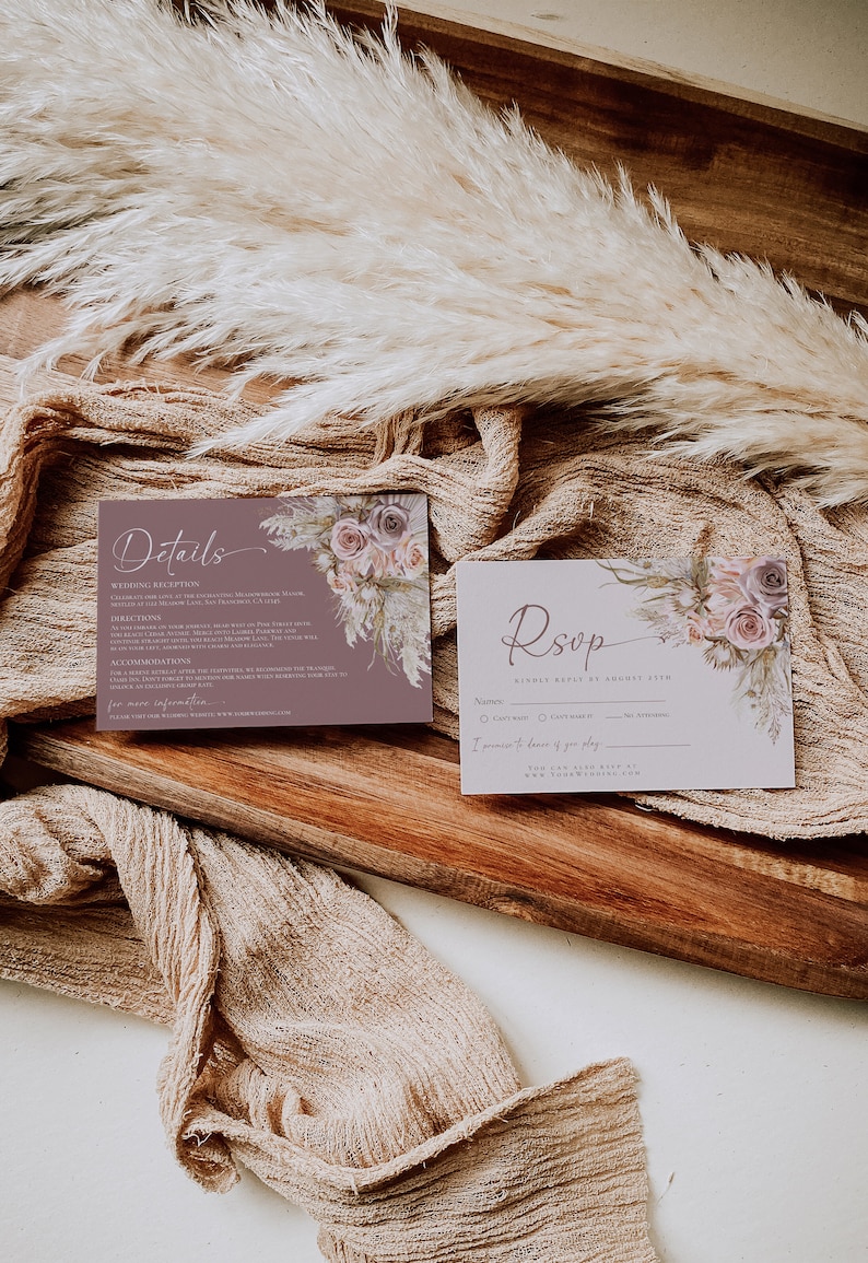 May include: A rectangular details card and a matching RSVP card featuring a mauve background, white script text, and a floral illustration of roses and pampas grass. The details card includes text about a wedding reception, directions, and accommodations.