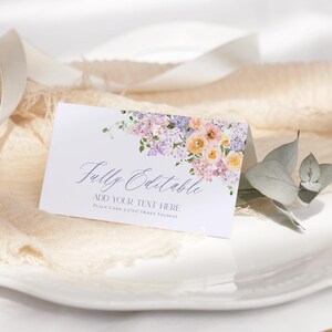 May include: A white place card with a watercolor floral design in shades of purple, pink, and yellow. The text "Fully Editable" and "Add Your Text Here" is printed in purple. The card is 3 1/2 x 5 1/2 inches when folded.