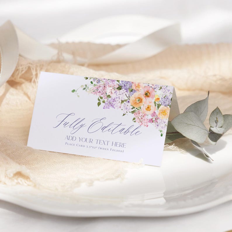 May include: A white place card with a watercolor floral design in shades of purple, pink, and yellow. The text "Fully Editable" and "Add Your Text Here" is printed in purple. The card is 3 1/2 x 5 1/2 inches when folded.