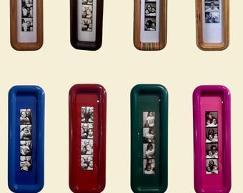 May include: Eight rectangular photo frames arranged in two rows. The top row features four wooden frames in varying natural tones and one multi-coloured striped frame. The bottom row contains four solid-coloured glossy frames in blue, red, green, and pink.