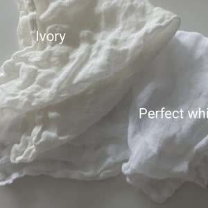 May include: Two pieces of white fabric, one labelled "Ivory" and the other labelled "Perfect white". The fabric is soft and textured, and the difference in colour is subtle.