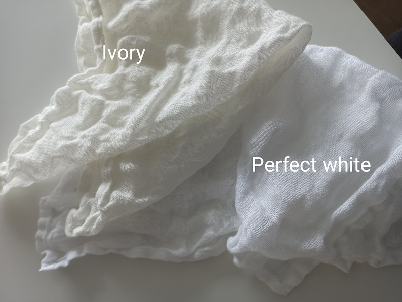 May include: Two pieces of white fabric, one labelled "Ivory" and the other labelled "Perfect white". The fabric is soft and textured, and the difference in colour is subtle.