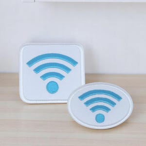 Peut inclure: Deux patchs brodés blancs avec un symbole Wi-Fi bleu. Le plus grand patch est carré et le plus petit est rond.
