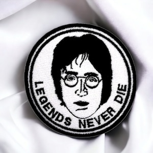 Op de afbeelding: Zwart-witte geborduurde patch met een portret van John Lennon met de tekst "Legends Never Die" rond de rand.