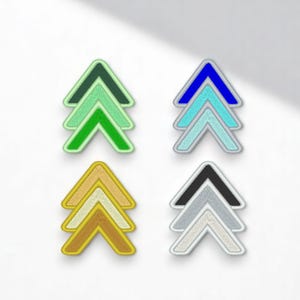 Peut inclure: Quatre ensembles de patchs fléchés brodés en différentes combinaisons de couleurs : vert, bleu, or et gris. Chaque ensemble comprend trois flèches superposées, avec des coutures blanches et une bordure blanche. Les patchs sont sur fond blanc.