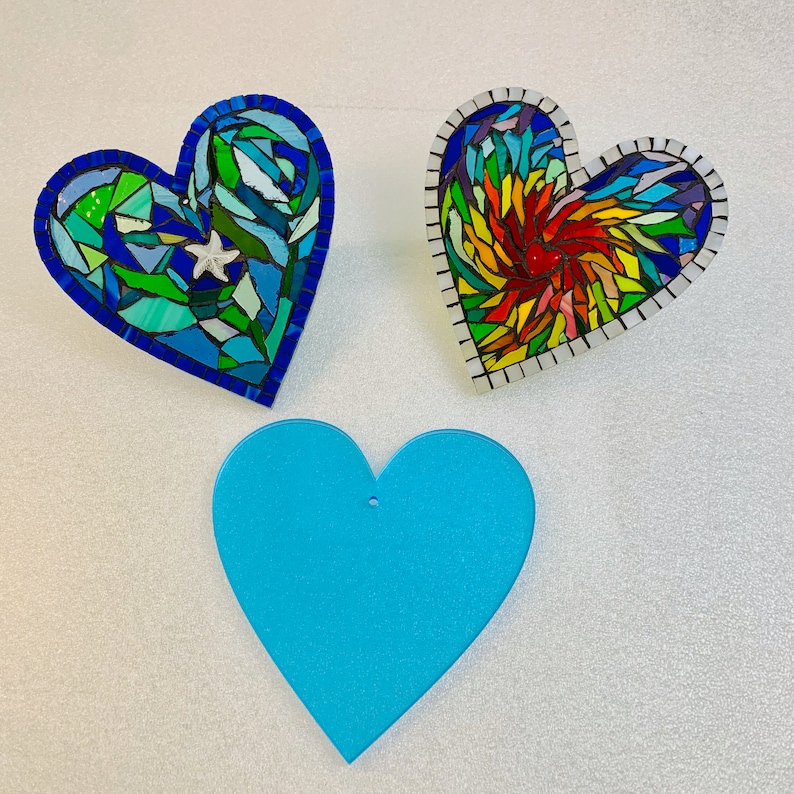 May include: Three heart-shaped decorations, one blue with a white star, one rainbow-coloured, and one solid blue.