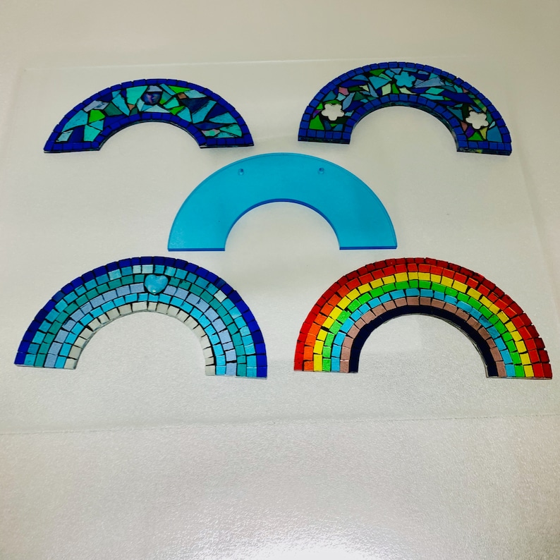 May include: Five rainbow arches made of mosaic tiles. The arches are in various colours, including blue, green, yellow, orange, and red. The arches are arranged in a semi-circle pattern.