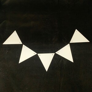 May include: A white triangle banner with six triangles connected together. The banner is hanging on a black fabric background.