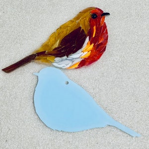May include: A stained glass mosaic of a robin bird with red, orange, yellow, and brown glass pieces. The bird is perched on a light blue silhouette of a bird.