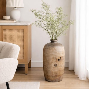 Puede incluir: Un jarrón de madera rústico grande, con base ancha y cuello estrecho, lleno de delicadas ramitas verdes. El jarrón es de color marrón claro y tiene un acabado natural y texturizado. El jarrón mide aproximadamente 91 cm de alto. Decoración del hogar.