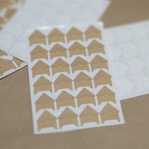May include: A sheet of brown corner photo stickers with adhesive on the back. The stickers are arranged in a grid pattern on a white sheet.
