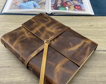Könnte beinhalten: Ein braunes, ledergebundenes Tagebuch mit einem hellbraunen Lederband und einer personalisierten Inschrift, die "Ollie & Hannah I love you more" lautet.