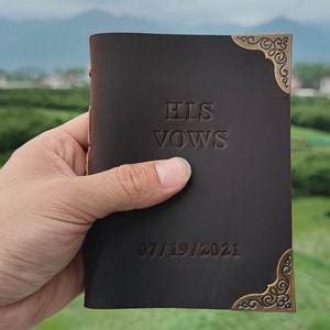 Puede incluir: Un diario de cuero marr&oacute;n con detalles dorados en las esquinas. La portada est&aacute; grabada con el texto "HIS VOWS" y la fecha "07/19/2021".