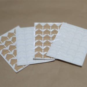 May include: Three sheets of brown and white corner stickers for scrapbooking or photo albums. Each sheet has a different pattern of corner stickers.