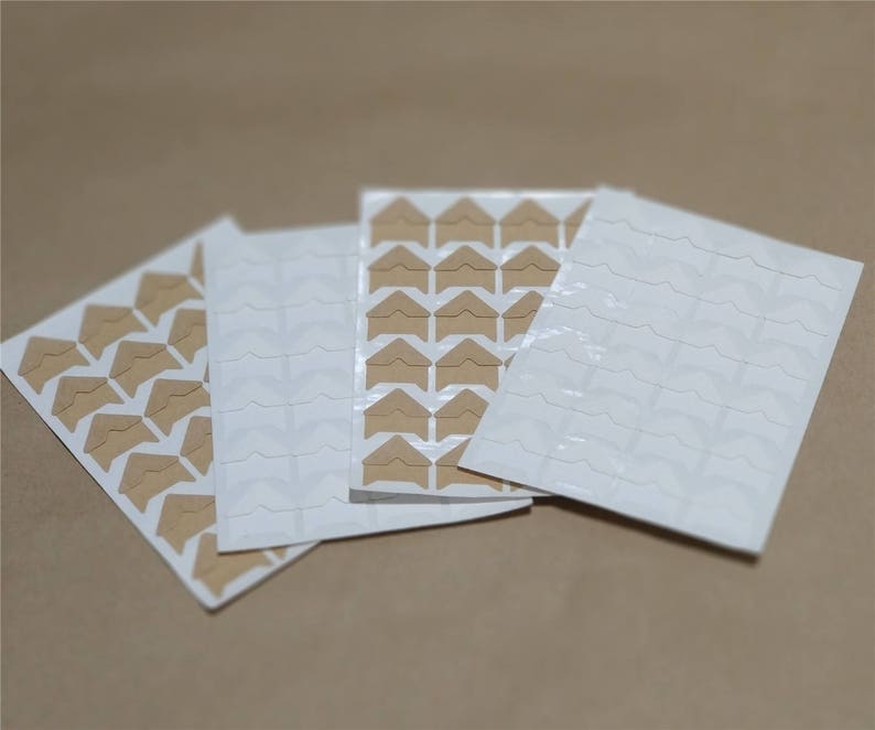 May include: Three sheets of brown and white corner stickers for scrapbooking or photo albums. Each sheet has a different pattern of corner stickers.